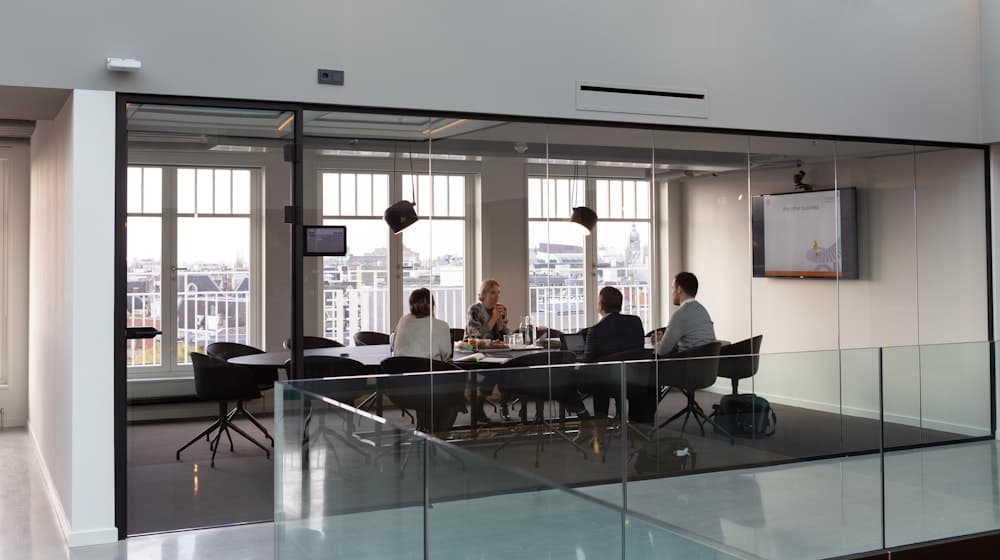 Hiring panel reviewing candidate results in a glass-walled meeting room